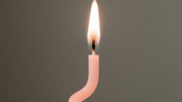 burning pink candle against gray background